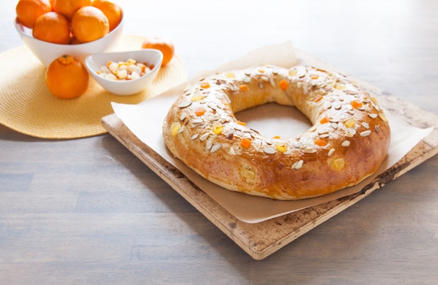 A King's Ring on parchment beside a bowl of oranges and dried fruit.