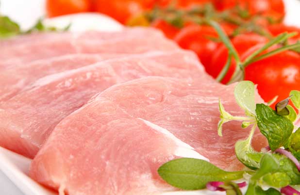 Sliced turkey with herbs and tomatoes on a vine.