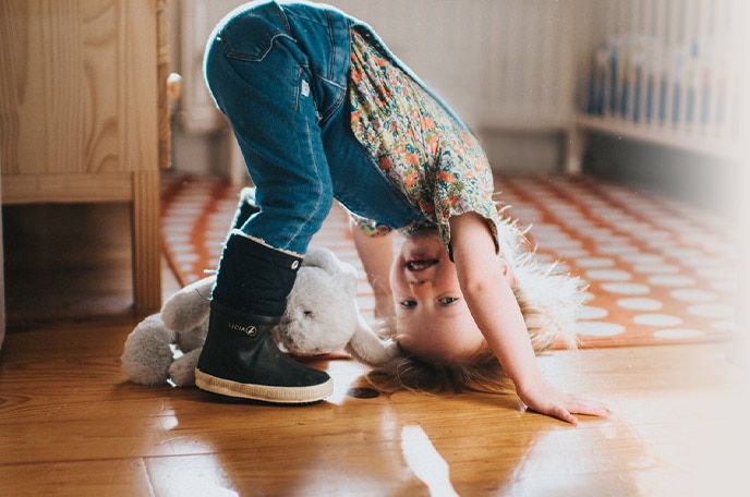 A young girl with her hands on the ground about to do a somersault.