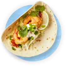 Overhead close up of one shrimp taco on a flour tortilla with a blue background.