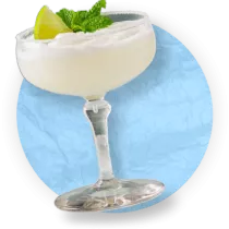 Primer plano de un cóctel margarita helado sobre un fondo azul.