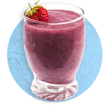 Close up of a clear glass with purple smoothie filled to the top with a strawberry garnish, on a blue background.