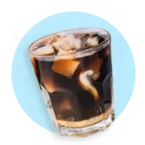 A glass of iced coffee with creamer on a light blue circle.