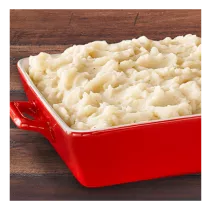 A red baking dish filled with creamy mashed potatoes.