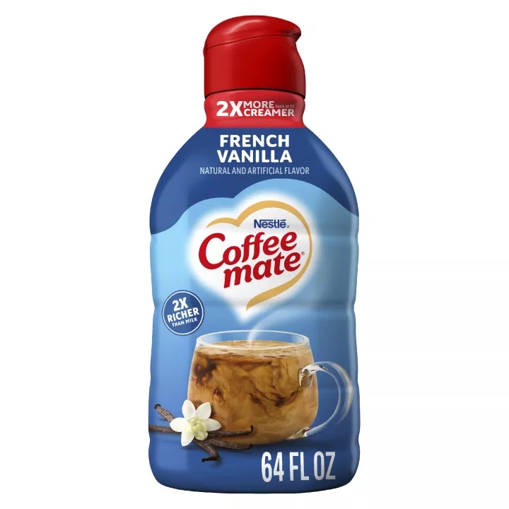 A bottle of French Vanilla Liquid Creamer with a red cap and blue label above a mug and vanilla beans.