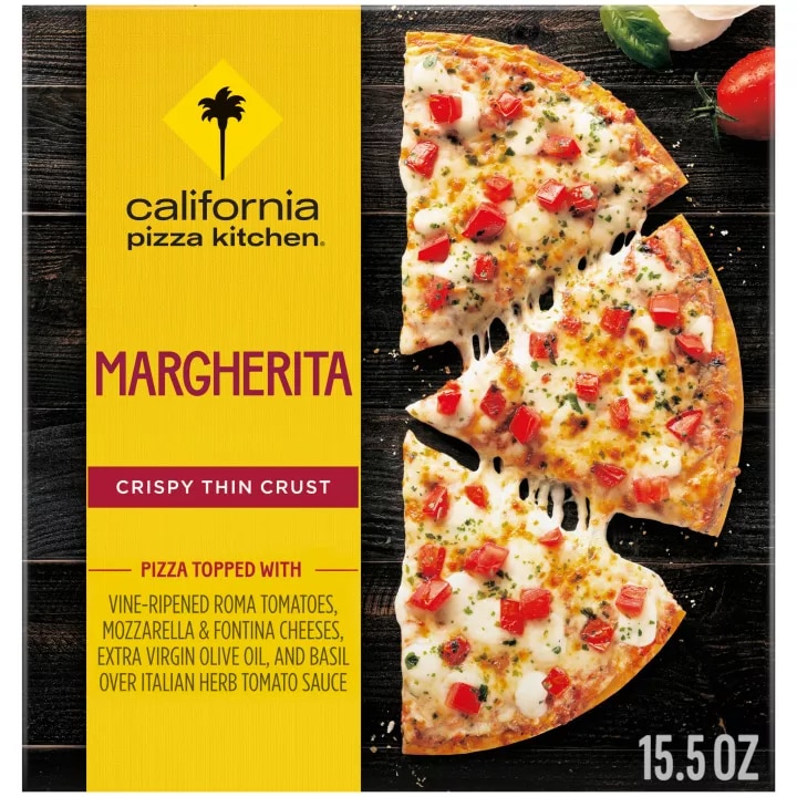 Box of Margherita Pizza with half a pizza, tomato, mozzarella, and basil on a black wooden surface.