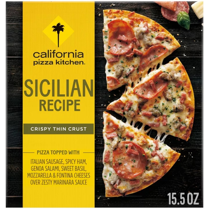 Box of Sicilian Recipe Pizza with half a pizza, salami, basil, pepperoni, and parmesan on a black wooden surface.