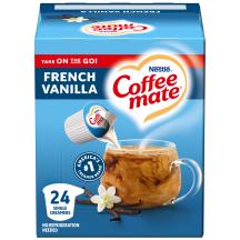 Una caja azul de porciones individuales de creamer Coffee mate Vanilla con una etiqueta azul encima de una taza de café, vaina de vainillas y el logotipo del producto.