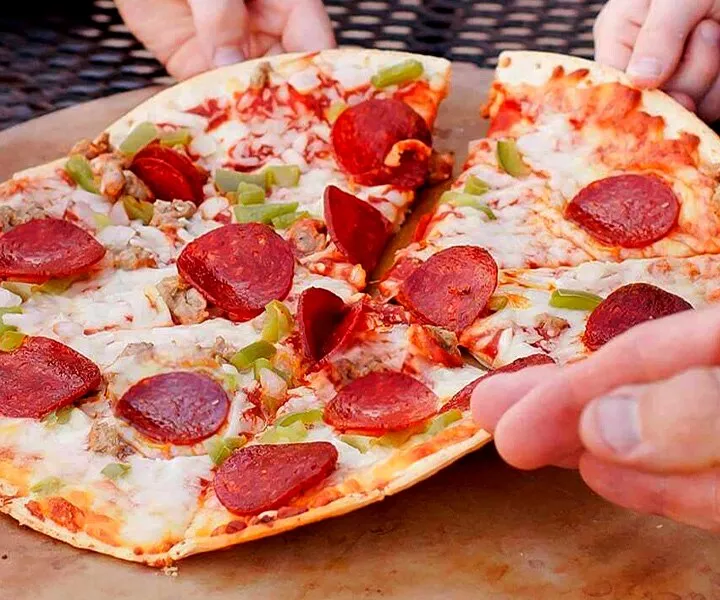 Hands lift slices of Jack's original thin crust supreme pizza from a cardboard tray.